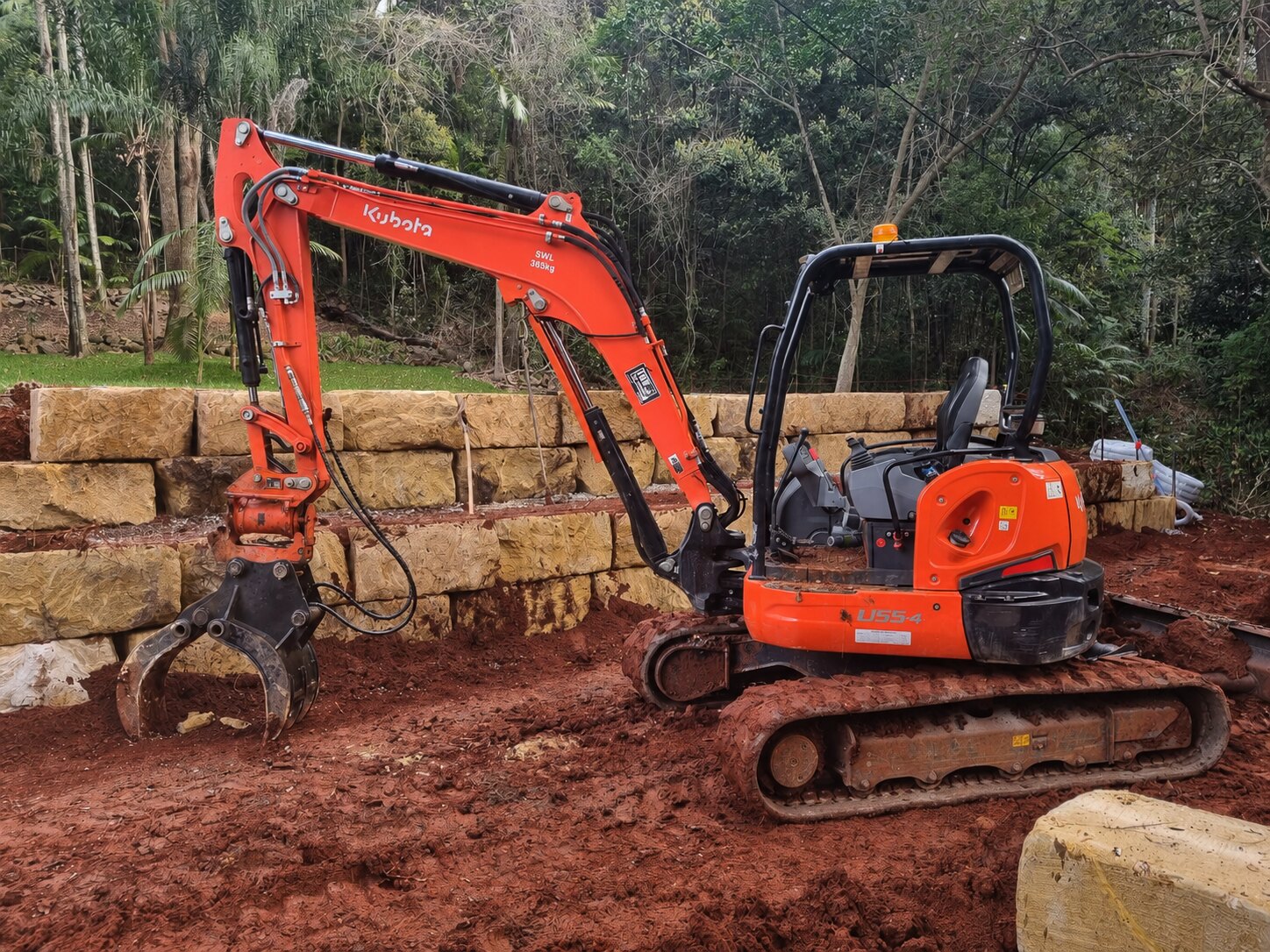 Kubota excavator with hydraulic grab on a retaining wall site